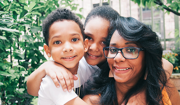 Two children and their mother smile for a picture taken outside.