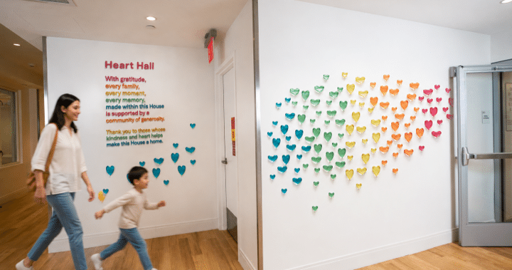 A woman and a child walk through a hallway with hearts on the walls.